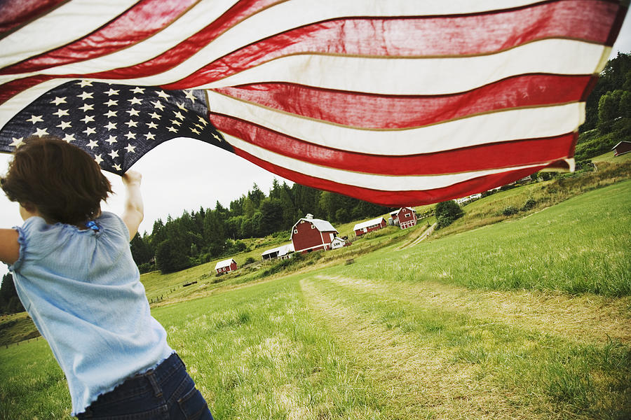 Girl running with American flag on farm Photograph by Blend Images - Ned Frisk