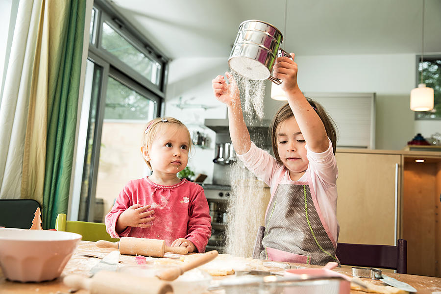 Girl sieving flour in kitchen Photograph by Nils Hendrik Mueller