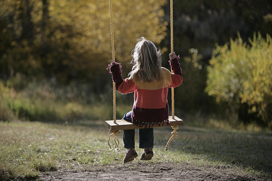 Girl sitting on a swing Photograph by Comstock Images