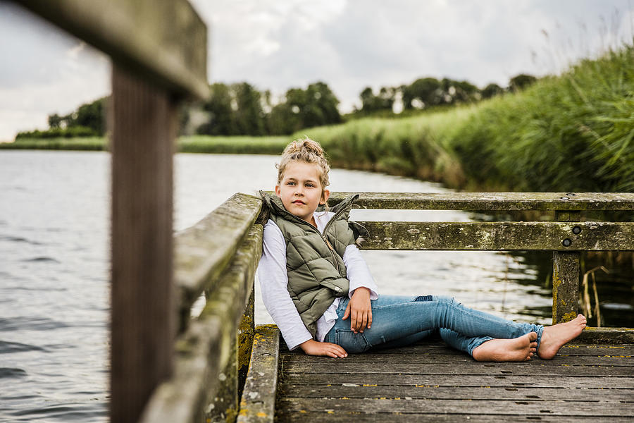 Girl sitting on jetty at a lake Photograph by Westend61