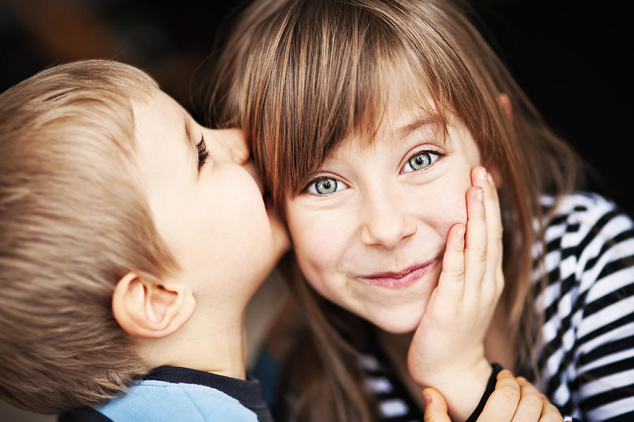 Girl smiles as little brother whispers in her ear Photograph by Imgorthand