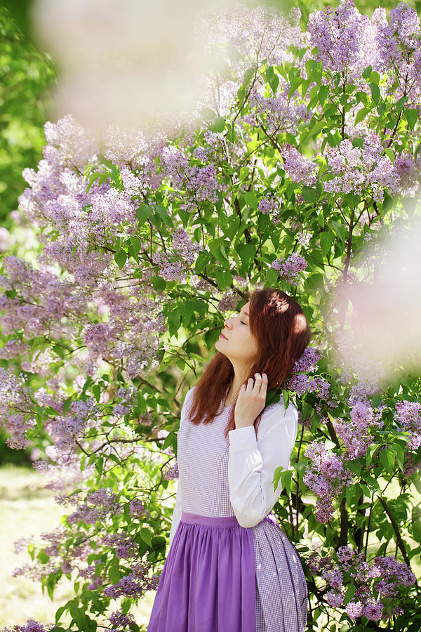 Girl sniffing a lilac under a bush in the garden Photograph by Iuliia Malivanchuk