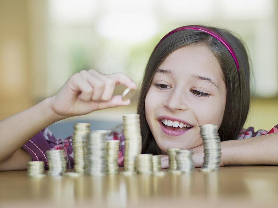 Girl stacking coins Photograph by Chris Ryan