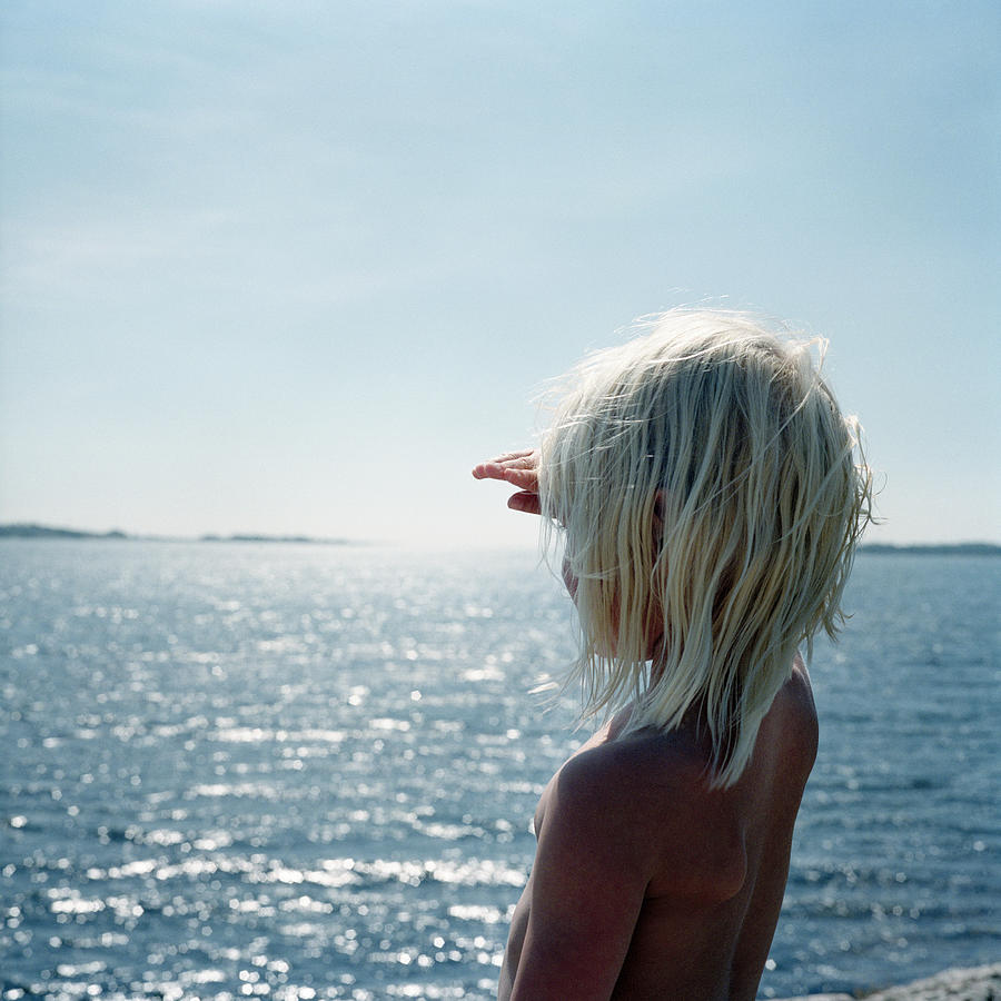 Girl standing by the ocean, Blekinge, Sweden. Photograph by Johner Images