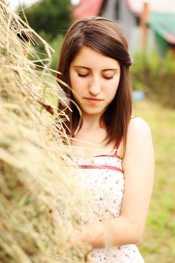 Girl standing next to a stack of hay being sad Photograph by Im limited edition