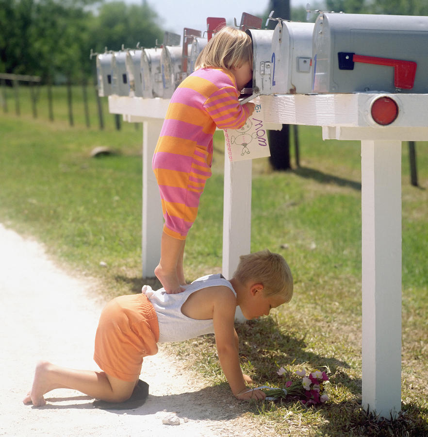 Girl standing on brothers back and peering into mailbox Photograph by Jasper Cole