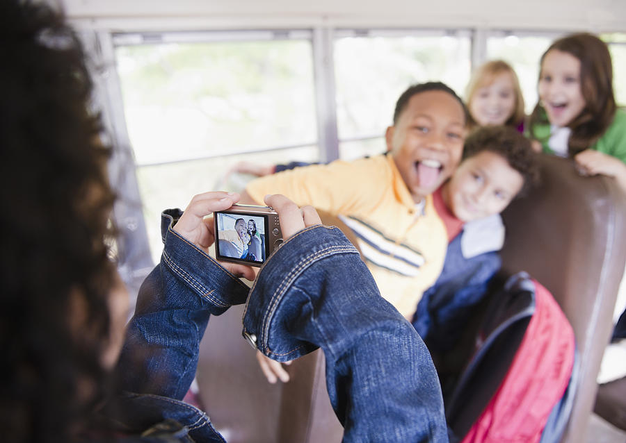 Girl taking photographs on school bus Photograph by JGI/Jamie Grill