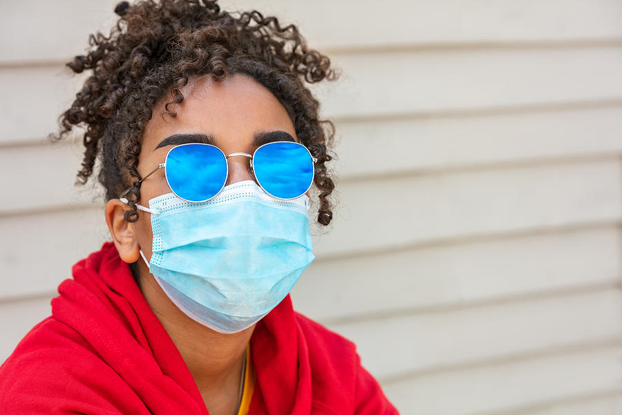 Girl teenager teen mixed race biracial African American female young woman wearing blue sunglasses and face mask in Coronavirus COVID-19 pandemic Photograph by Dmbaker