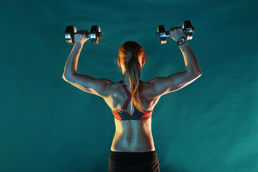 Girl training with dumbbells, back view, green ba Photograph by Stanislaw Pytel
