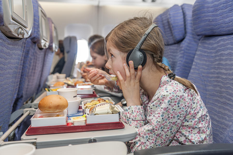 Girl watching movie on airplane while eating airline meal Photograph by PhotoAlto/Thierry Foulon