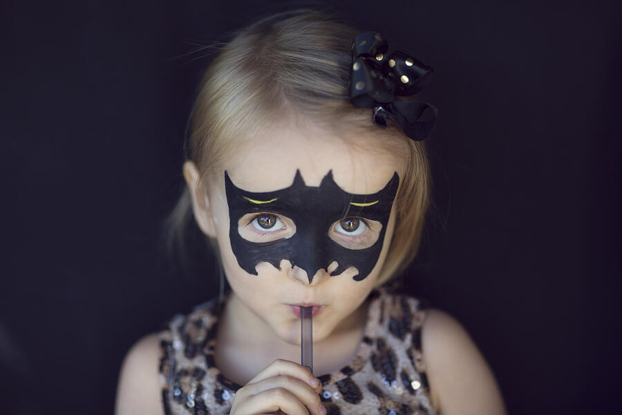 Girl with bat shaped Halloween face paints, drinking through a straw Photograph by Elva Etienne