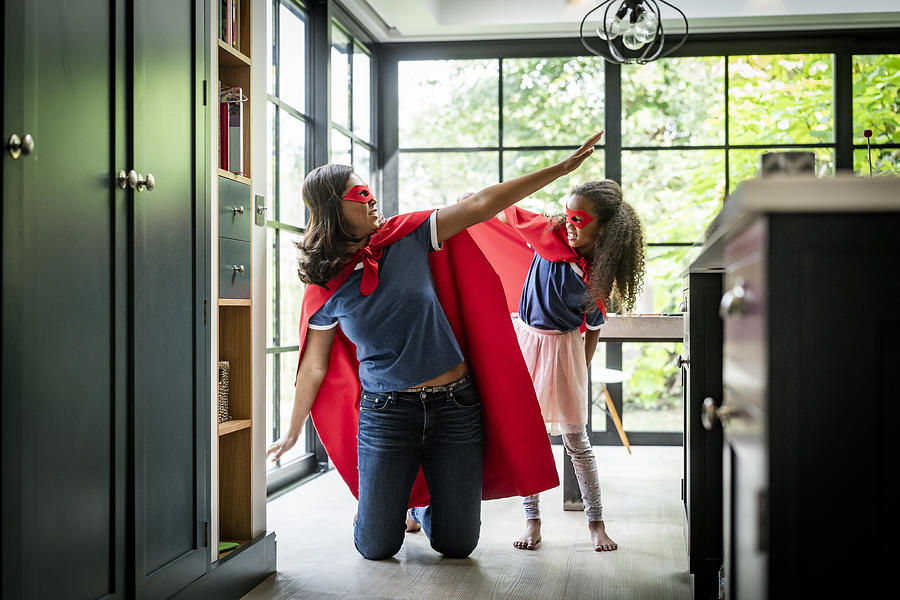 Girl with mother in red superhero costume at home Photograph by Stígur Már Karlsson /Heimsmyndir