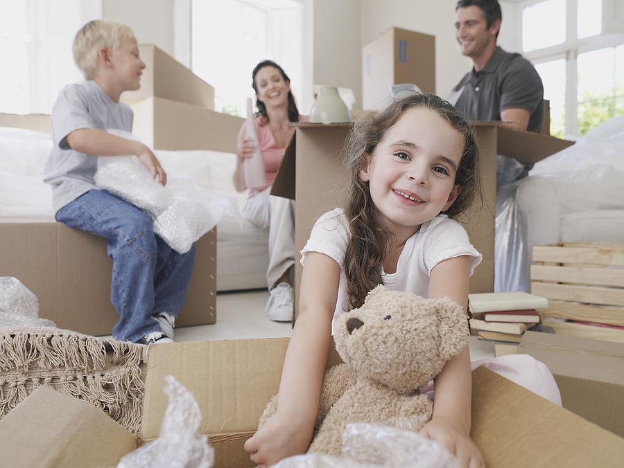 Girl with teddy bear in cardboard box with brother and parents in background Photograph by Chris Ryan