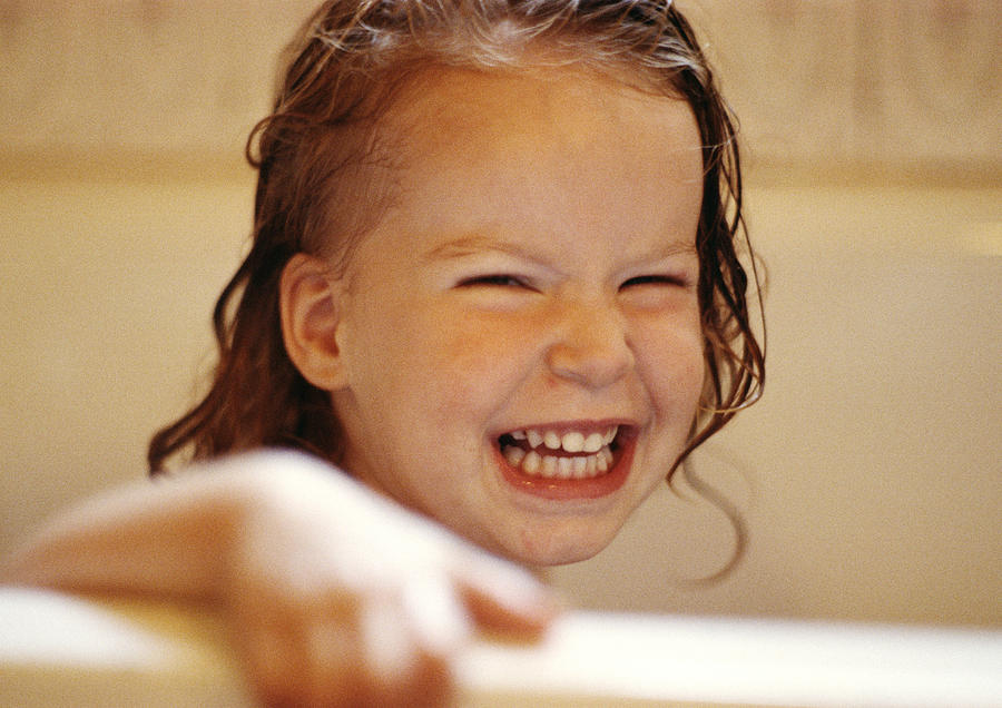 Girl with wet hair holding edge of bathtub, smiling Photograph by Corinne Malet