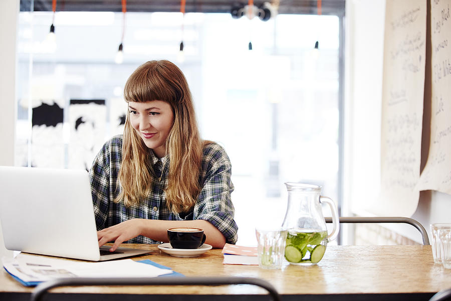 Girl working on laptop in trendy coffee shop Photograph by Ezra Bailey Girl working on laptop in trendy coffee shop Photograph by Ezra Bailey