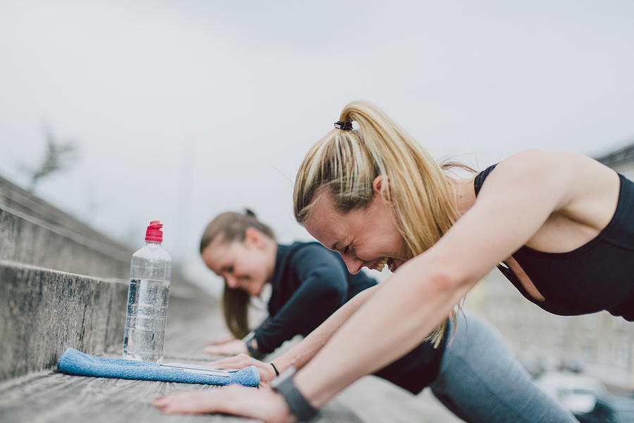 Girlfriends doing push-ups together Photograph by Guido Mieth
