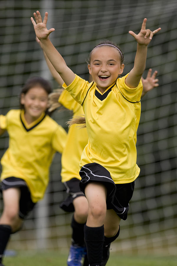 Girls (8-13) playing football, laughing Photograph by John Giustina