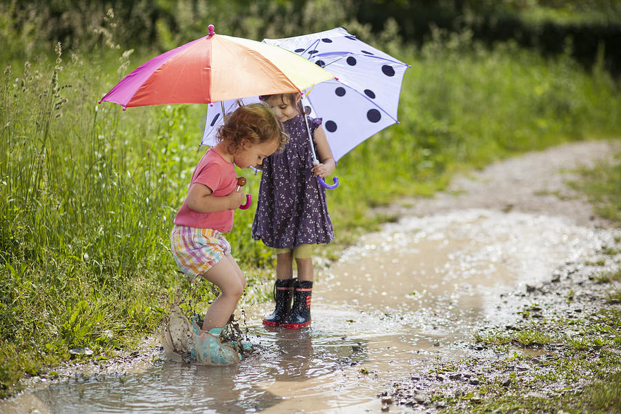 Girls holding umbrellas and playing in water Photograph by Simonkr