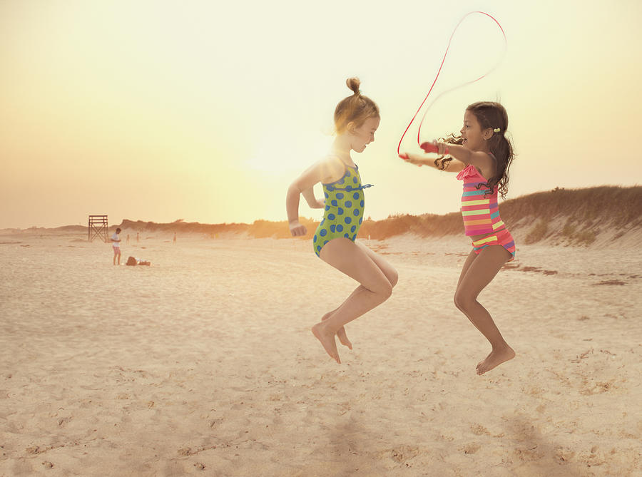 Girls jumping rope on beach Photograph by Jose Luis Pelaez Inc