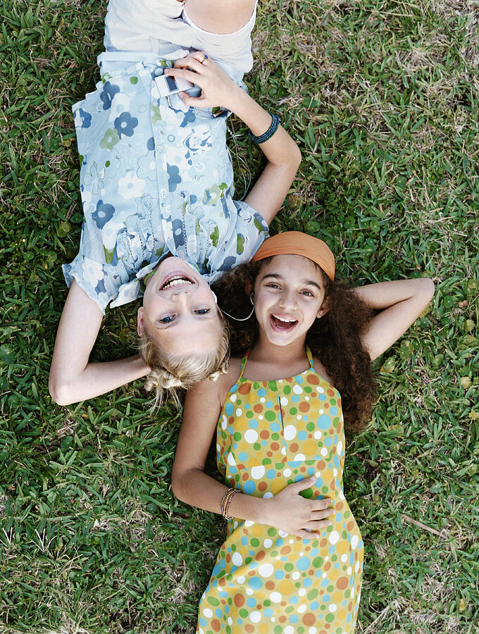 Girls Lying on Grass With Their Hands Behind Their Heads Photograph by Digital Vision.