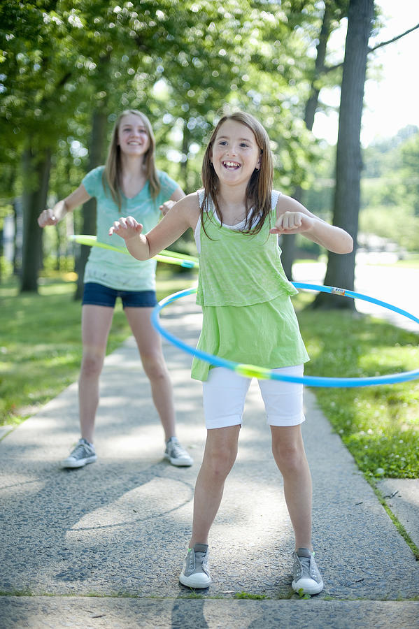 Girls Playing with Hoola Hoops on Sidewalk Photograph by Yellow Dog Productions