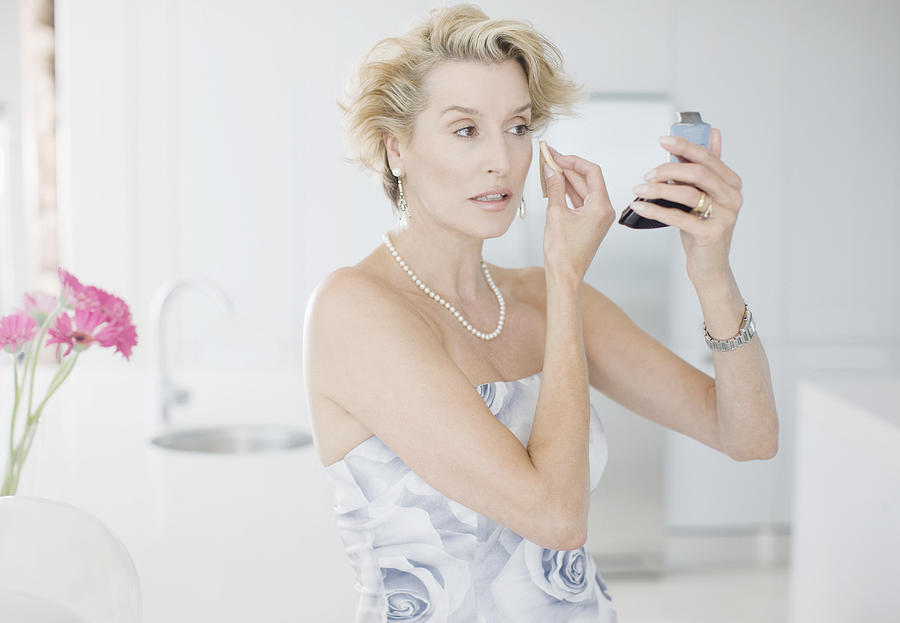 Glamorous woman putting on makeup Photograph by Paul Bradbury