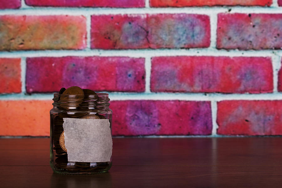 Glass jar on wooden surface filled with old coins Photograph by Christopherhall