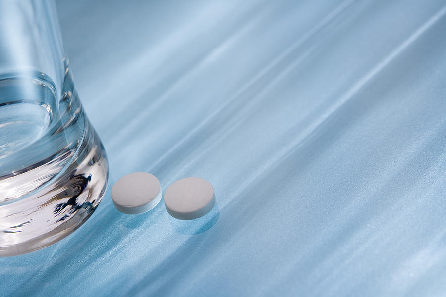 Glass of water and pills Photograph by Comstock Images