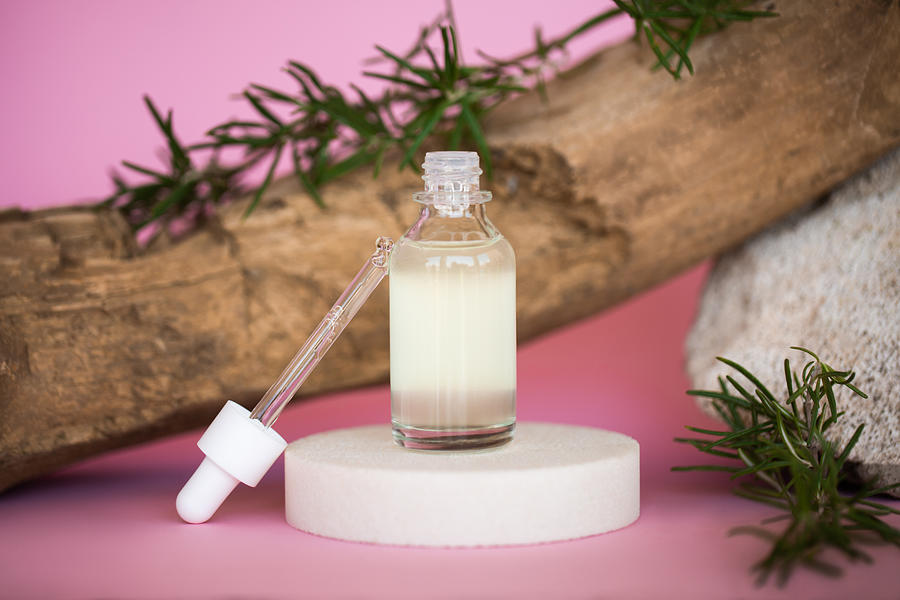 Glass pipette and bottle of essential oil near organic materials on pink background. Trendy selfcare products of the year Photograph by Anna Efetova