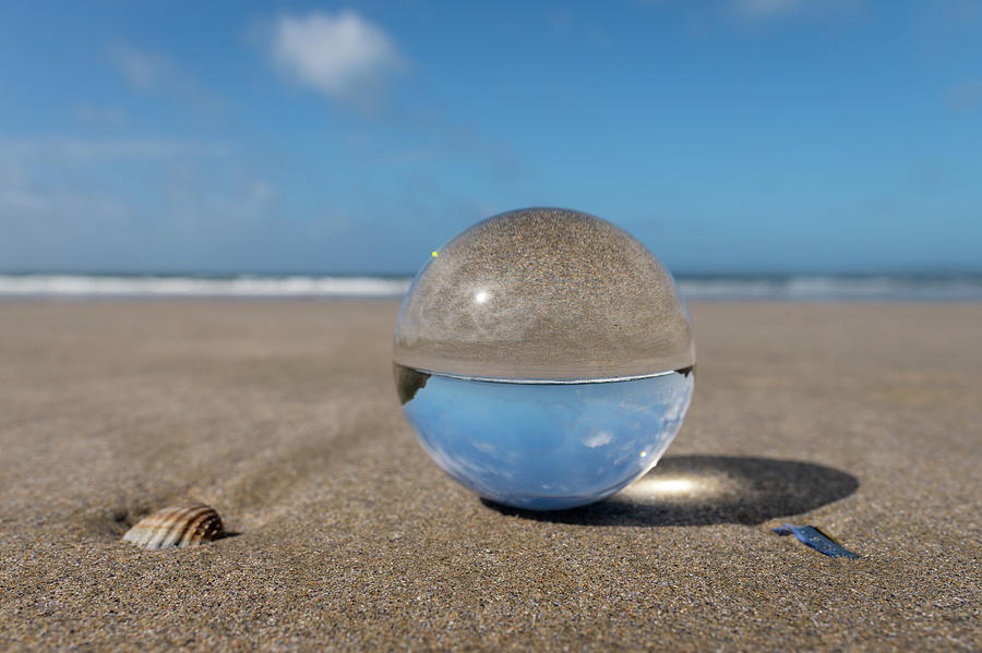 Glass sphere lying on a beach on a sunny day Photograph by Stefan