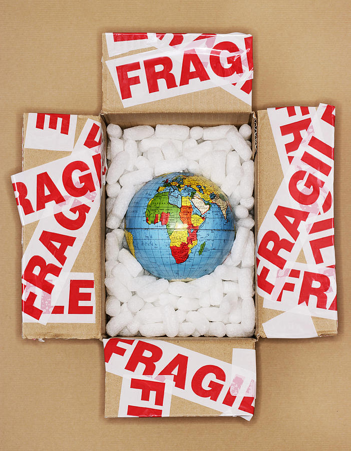 Globe in open packing box covered in tape marked fragile Photograph by Harrison Eastwood