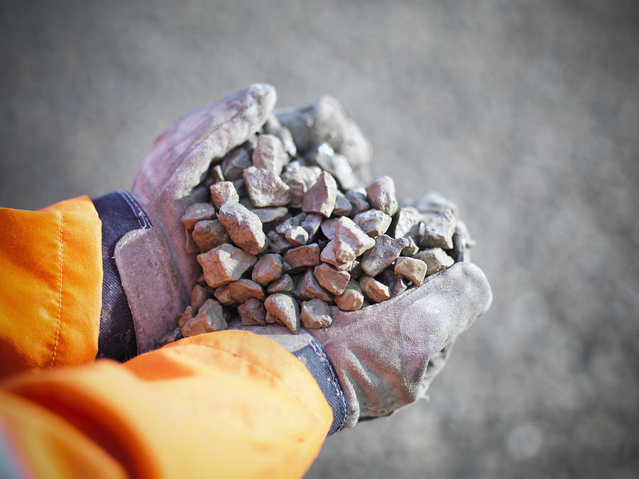 Gloved hands holding crushed stones in quarry site Photograph by Monty Rakusen