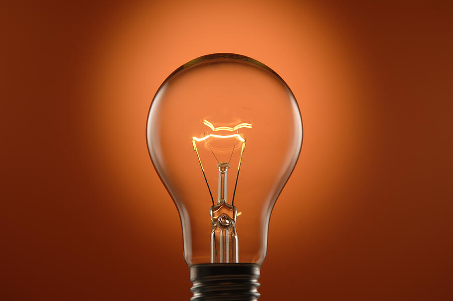 Glowing Lightbulb on Orange Background Photograph by Peepo