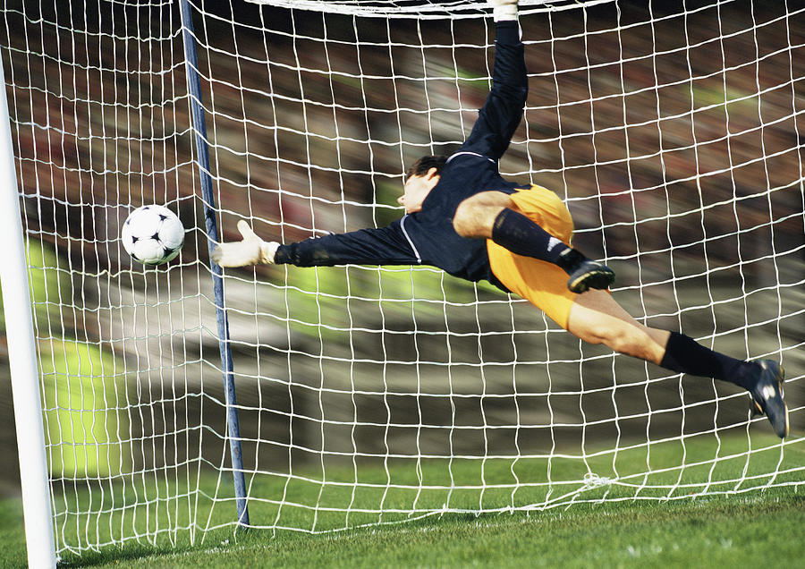 Goal keeper reaching for soccer ball. Photograph by Vincent Hazat