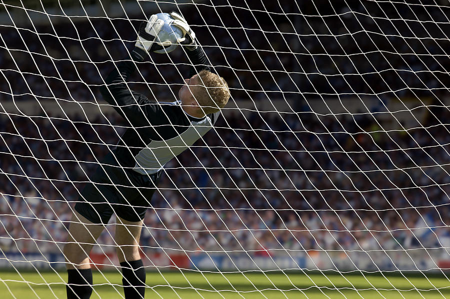 Goalkeeper attempting to prevent the ball entering the net at soccer match Photograph by Corbis/VCG