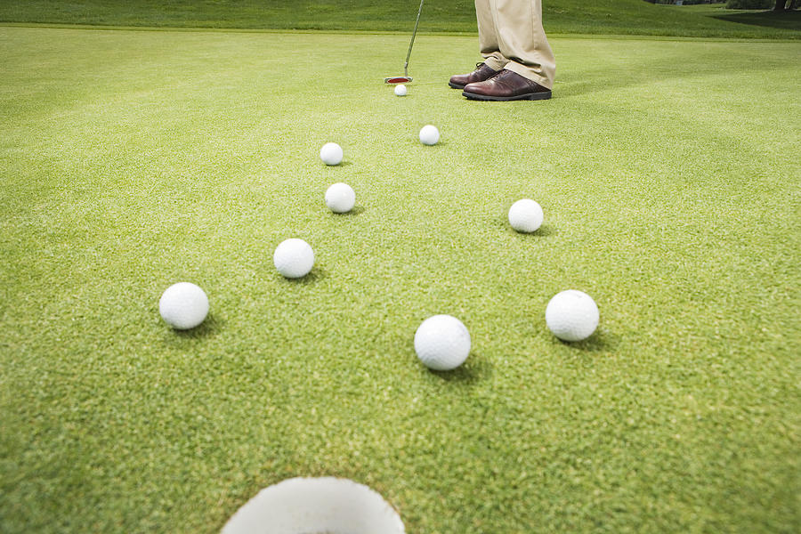 Golfer hitting ball through group of golf balls, low section Photograph by FangXiaNuo