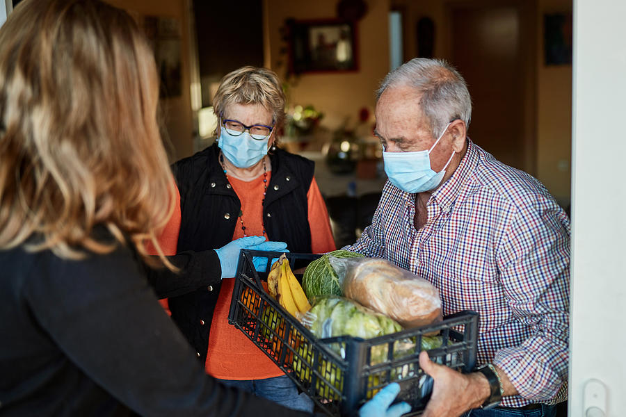 Grandchild delivers groceries to grandparents during pandemic at their home Photograph by Xavierarnau