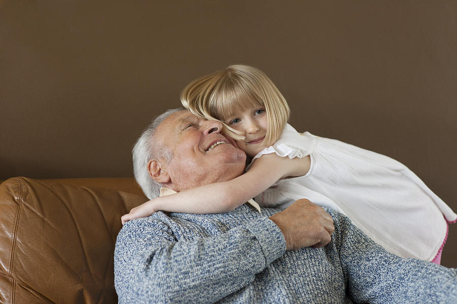 Granddaughter hugging Grandfather Photograph by Compassionate Eye Foundation/Natasha Alipour Faridani