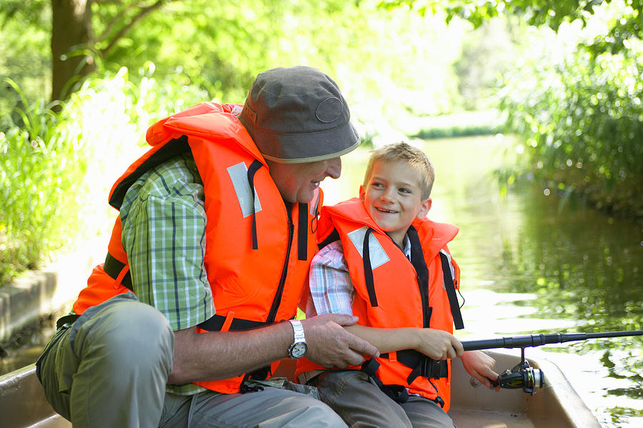 Grandfather and grandson (6-8) fishing from boat, smiling Photograph by Jochen Sand