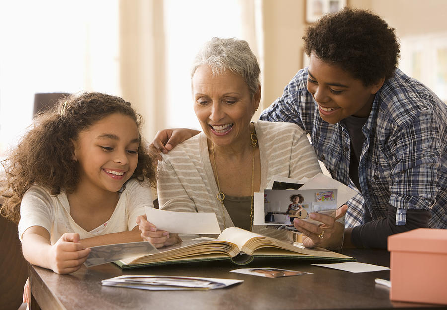 Grandmother and grandchildren looking at photographs Photograph by Jose Luis Pelaez Inc