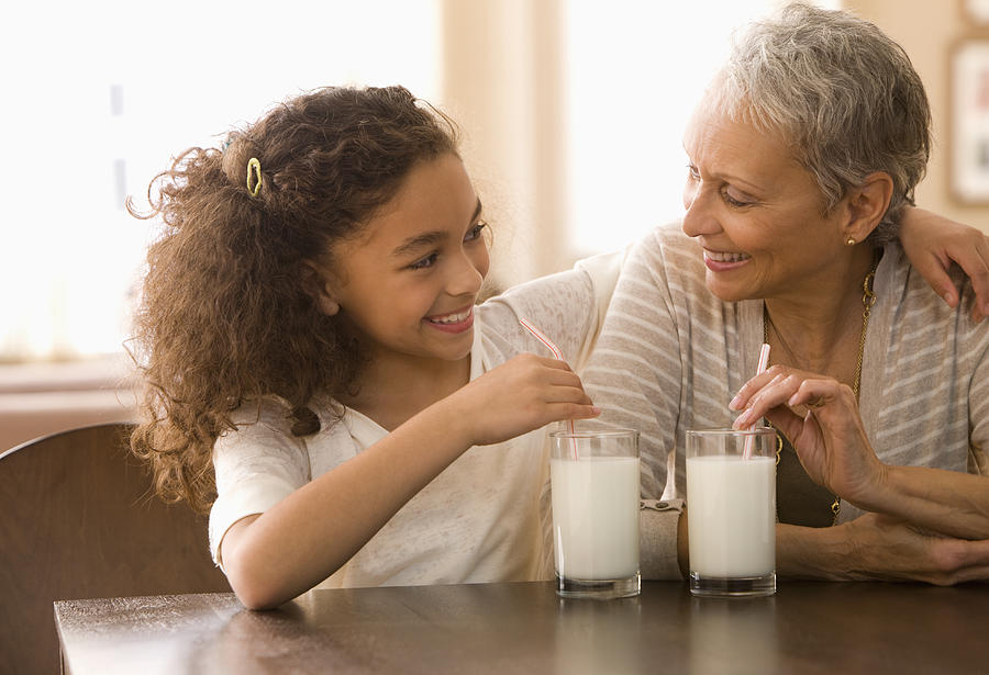 Grandmother and granddaughter drinking milk Photograph by Jose Luis Pelaez Inc