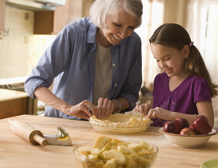 Grandmother and granddaughter making pie crusts Photograph by SelectStock