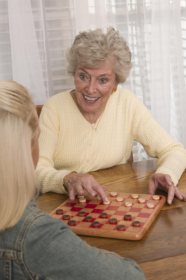 Grandmother and granddaughter playing checkers Photograph by Comstock Images