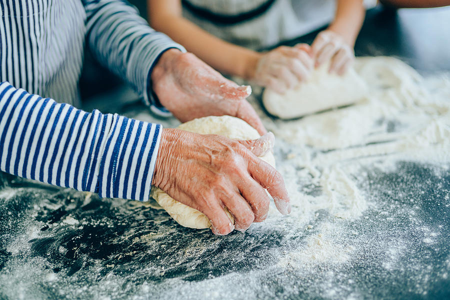 Grandmother teaching her granddaughter to make cookies Photograph by VioletaStoimenova