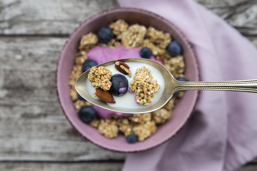 Granola, almonds, blueberry and milk on spoon, close-up Photograph by Westend61