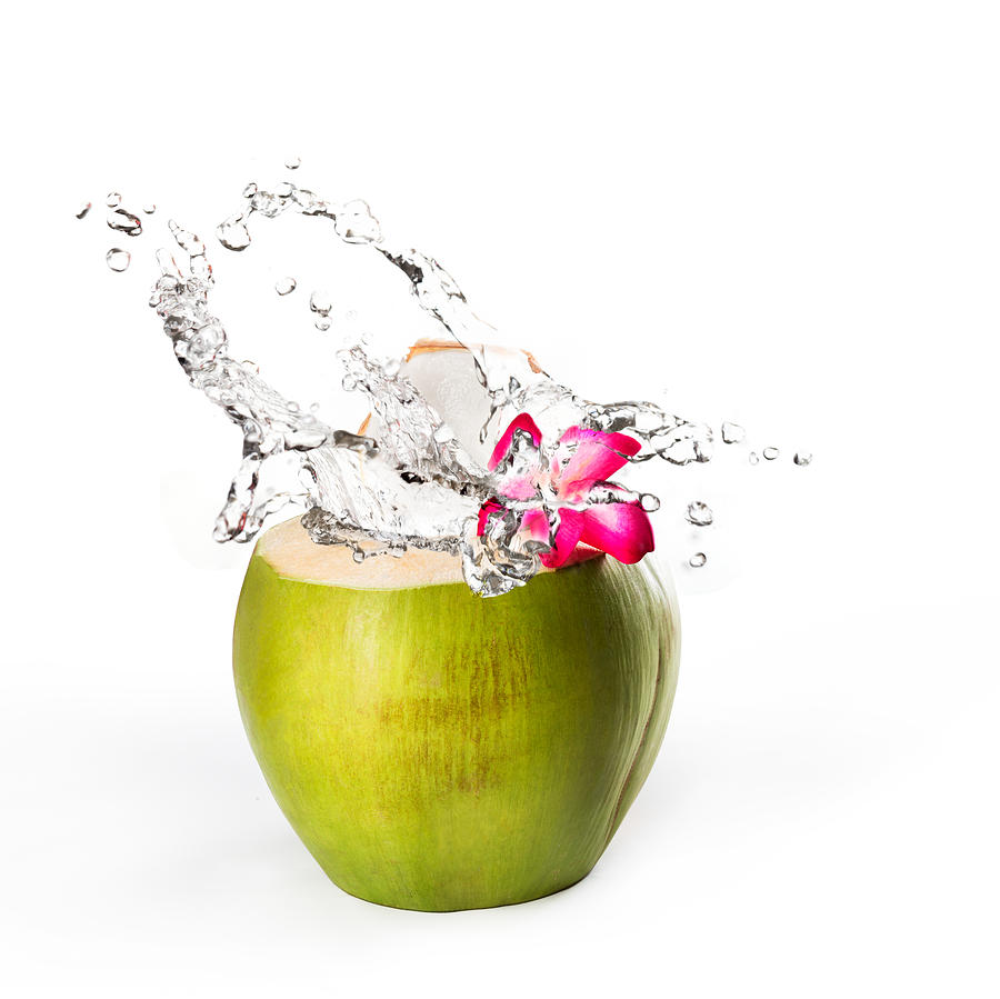 Green coconut with water splash, Isolated over white Photograph by Busakorn Pongparnit