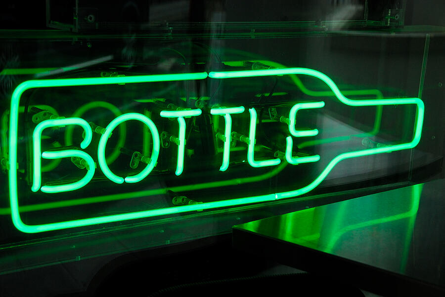 Green neon sign shaped as bottle in window of bar. Photograph by Lyn Holly Coorg