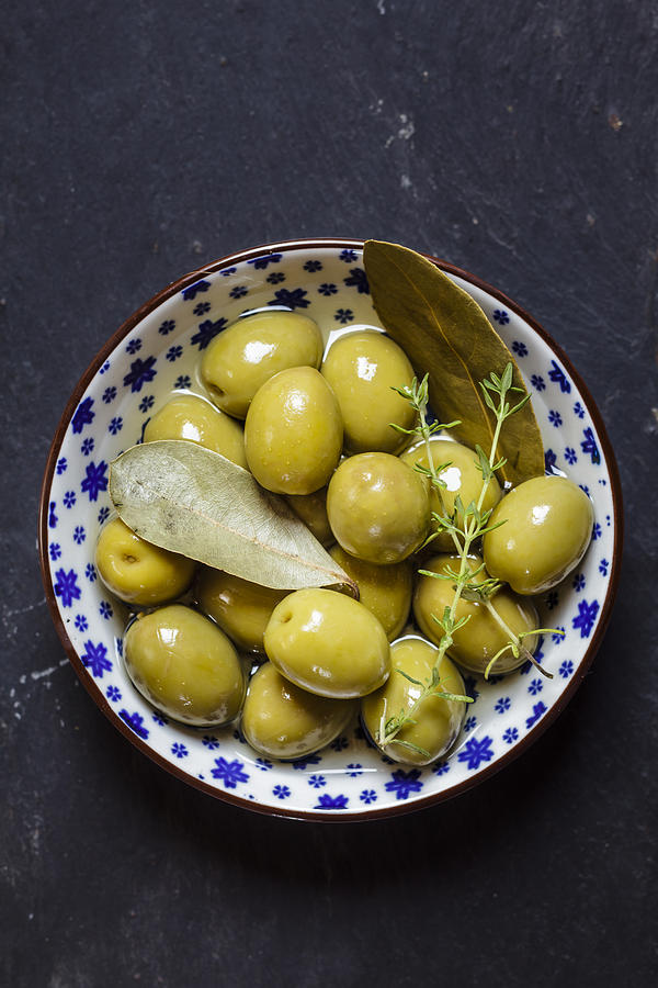 Green olives thyme and bay leaves in bowl Photograph by Westend61