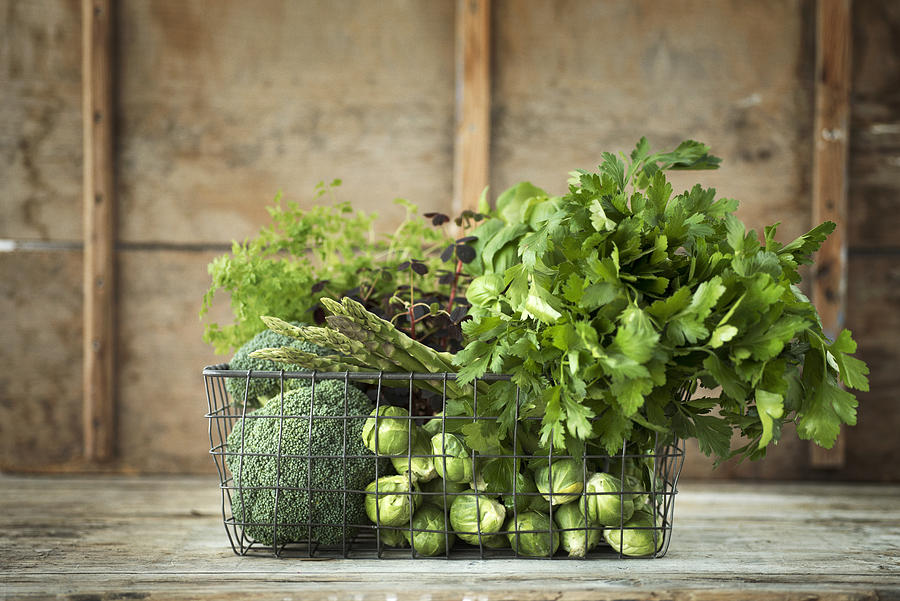 Green vegetables and herbs in wire basket Photograph by Johner Images