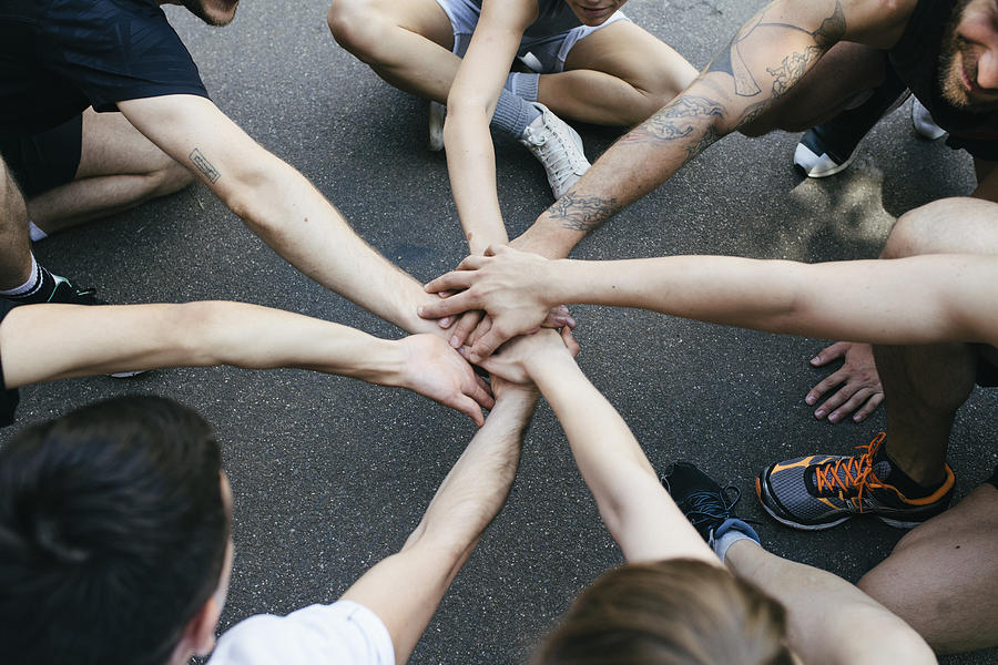 Group Of Athletes Bring Hands Together In Unity Before Friendly Outdoor Basketball Match Photograph by Hinterhaus Productions